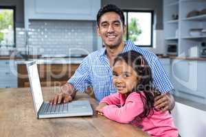 Smiling father using laptop with his daughter