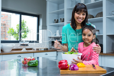 Smiling mother washing salad with her daughter