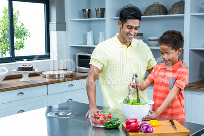 Smiling father preparing salad with his son