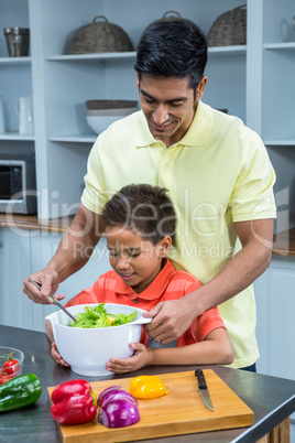 Smiling father preparing salad with his son