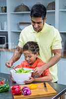 Smiling father preparing salad with his son