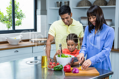 Happy family preparing salad in the kitchen