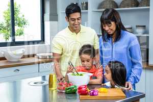 Happy family preparing salad in the kitchen