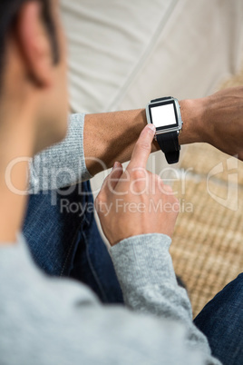 Handsome man using smartwatch on the sofa