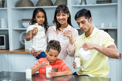 Happy family eating biscuits and drinking milk