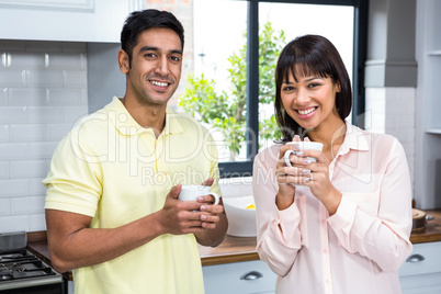 Happy couple smiling at the camera while holding cups