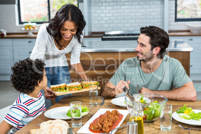 Smiling mother giving sandwiches to her son and husband