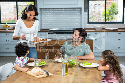 Smiling mother giving food to her children and husband