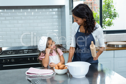 Smiling mother and daughter ready to cook in the kitchen