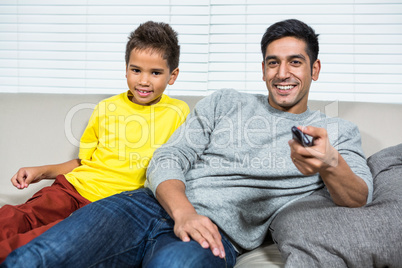 Smiling father ans son watching tv on the sofa