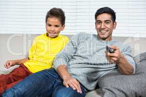 Smiling father ans son watching tv on the sofa