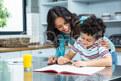 Kind mother helping her son doing homework