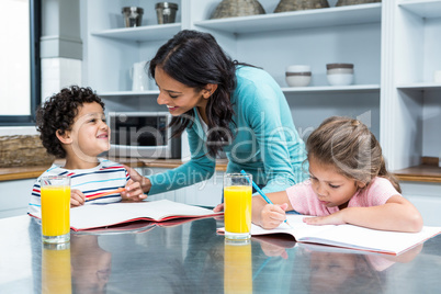 Kind mother helping her children doing homework
