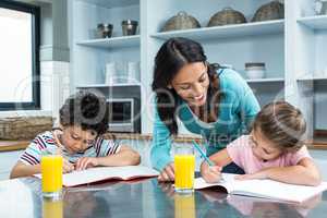 Kind mother helping her children doing homework