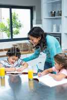 Kind mother helping her children doing homework