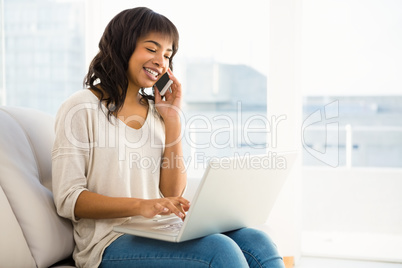 Smiling casual woman having a phone call while using laptop Smiling casual woman having a phone call while using laptop