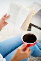 Cropped image of woman with coffee reading book