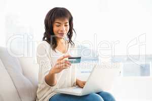 Smiling casual woman buying things with her laptop