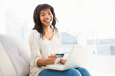 Smiling casual woman buying things with her laptop