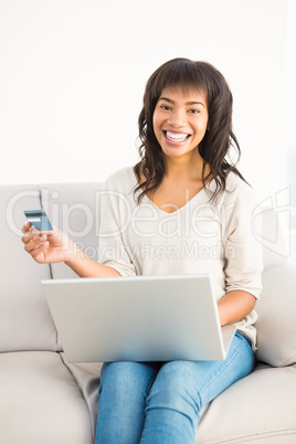 Smiling casual woman buying things with her laptop