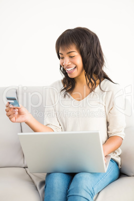 Smiling casual woman buying things with her laptop