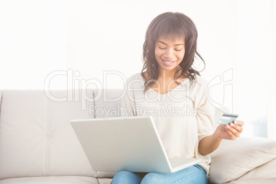 Smiling casual woman buying things with her laptop