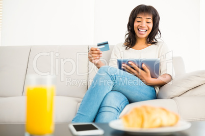 Casual woman using tablet while holding a card