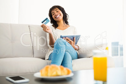 Casual woman using tablet while holding a card