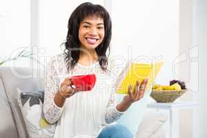 Smiling casual woman holding book and a cup of coffee