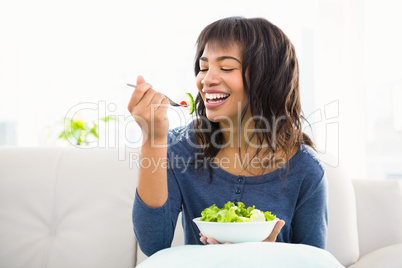 Casual smiling woman eating salad