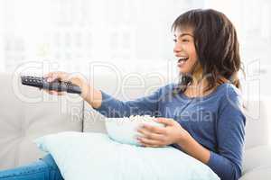 Smiling casual woman watching tv with popcorn