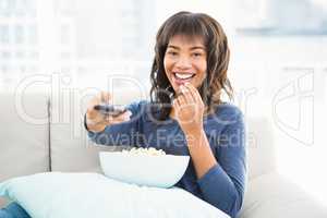 Smiling casual woman watching tv with popcorn