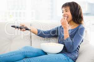 Smiling casual woman watching tv with popcorn