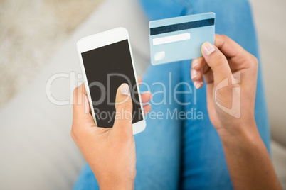 Close up view of a woman holding card and smartphone