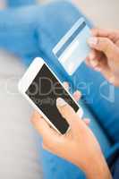 Close up view of a woman holding card and smartphone