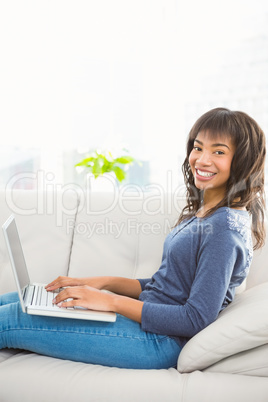 Casual smiling woman using laptop on the couch