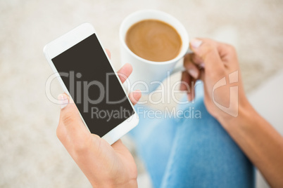 Close up view of a woman holding coffee and smartphone