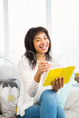 Casual smiling woman reading a yellow book