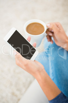 Close up view of a woman holding coffee and smartphone