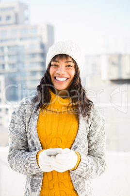 Smiling woman wearing winter clothes and typing on her phone