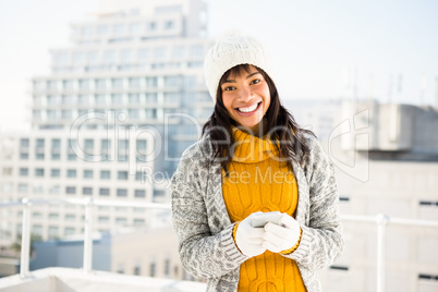 Smiling woman wearing winter clothes and typing on her phone