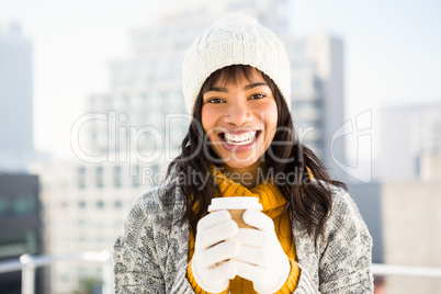 Smiling woman wearing winter clothes and holding coffee