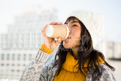 Smiling woman wearing winter clothes and drinking coffee