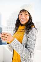 Smiling woman wearing winter clothes and holding coffee
