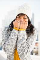 Smiling woman wearing winter clothes with hands on mouth