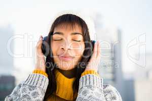 Smiling woman wearing winter clothes and listening music