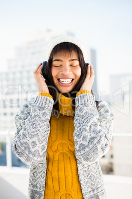 Smiling woman wearing winter clothes and listening music