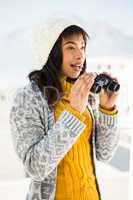 Smiling woman wearing winter clothes and looking into binoculars
