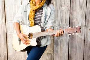Mid section of a smiling casual woman playing guitar