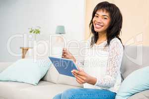 Casual smiling woman using tablet on the couch